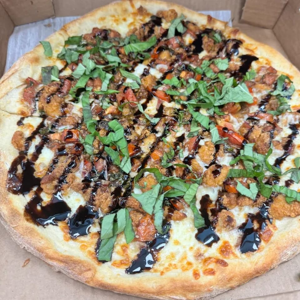 Pulcinella Pizza's chicken parmesan pizza with fresh basil and balsamic glaze in a delivery box.
