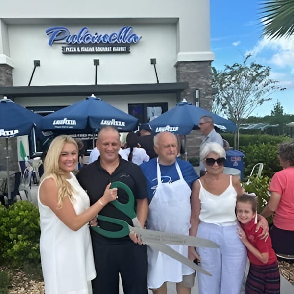Pulcinella Pizza and Italian Market ribbon cutting with five people holding giant scissors outside the restaurant.