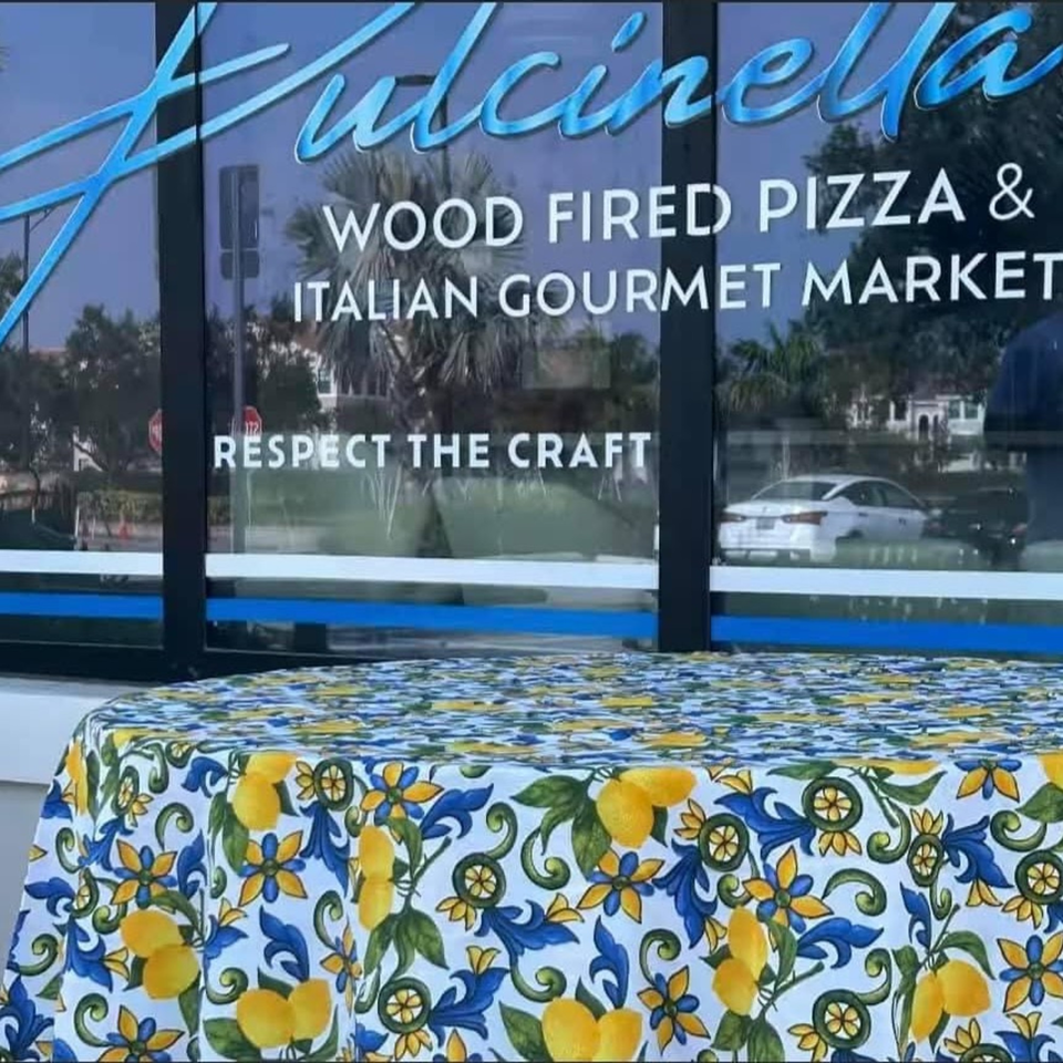 Pulcinella Pizza and Italian Market storefront with a lemon-patterned tablecloth in the foreground.