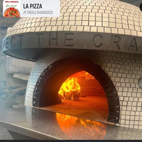 A Pulcinella Pizza wood-fired oven with a roaring fire inside, ready for baking.
